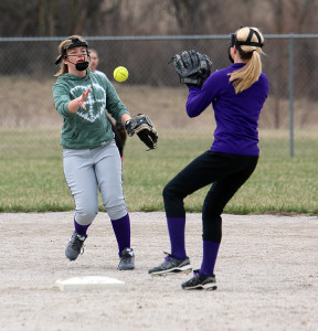 Louisburg's Cierra Rose underhands the ball to Blair Vohs as they turned a double play during practice. The Lady Cats open their season today in Paola.