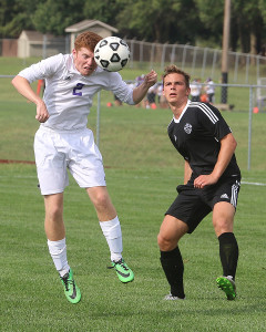 Louisburg defender Jacob Benne heads the ball away Tuesday during the Wildcats' home game with Paola.