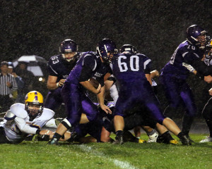 Senior Alex Dunn tries to keep his footing in the rain to get some extra yards while he gets blocks from teammates Jarod Woodward (63), Dustyn Rizzo (60) and T.J. Dover (70) on Friday in Louisburg.