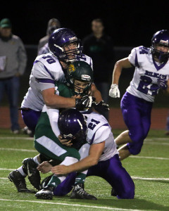 Louisburg's T.J. Dover (70) and Alex Dunn (21) team up on a tackle Friday in Basehor.