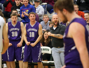Louisburg coach Jason Nelson gets excited on the Louisburg bench with players Korbin Hankinson (30) and Jake Hill after a late basket from T.J. Dover.