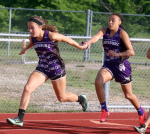 Megan Lemke (left) takes a handoff from teammate Jordon Leach during the 4x100 relay Friday at the Class 4A regional meet in Chanute.
