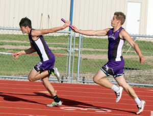 Louisburg's Quinn Rigney takes a handoff from teammate Ben Minster during the 4x100 relay Friday.