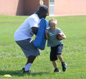 Tramaine Thompson holds the bag as he teaches a camper how to run through contact.