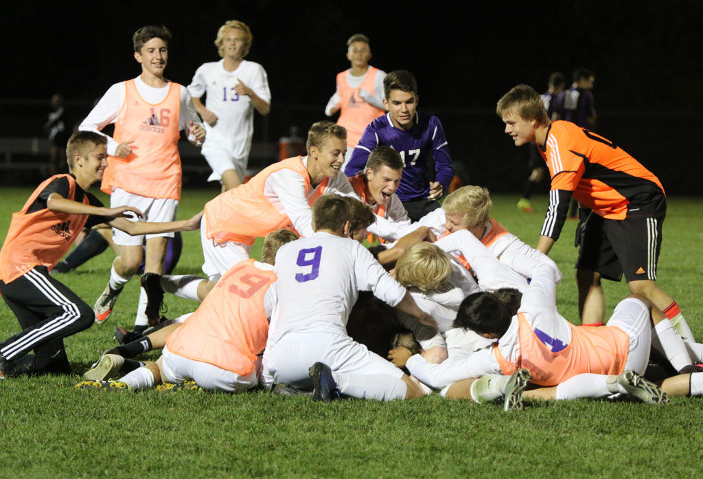 Members of the Louisburg High School soccer team dogpile on teammate Grant Ryals after he scored the game-winning goal in the second overtime Tuesday in Louisburg.