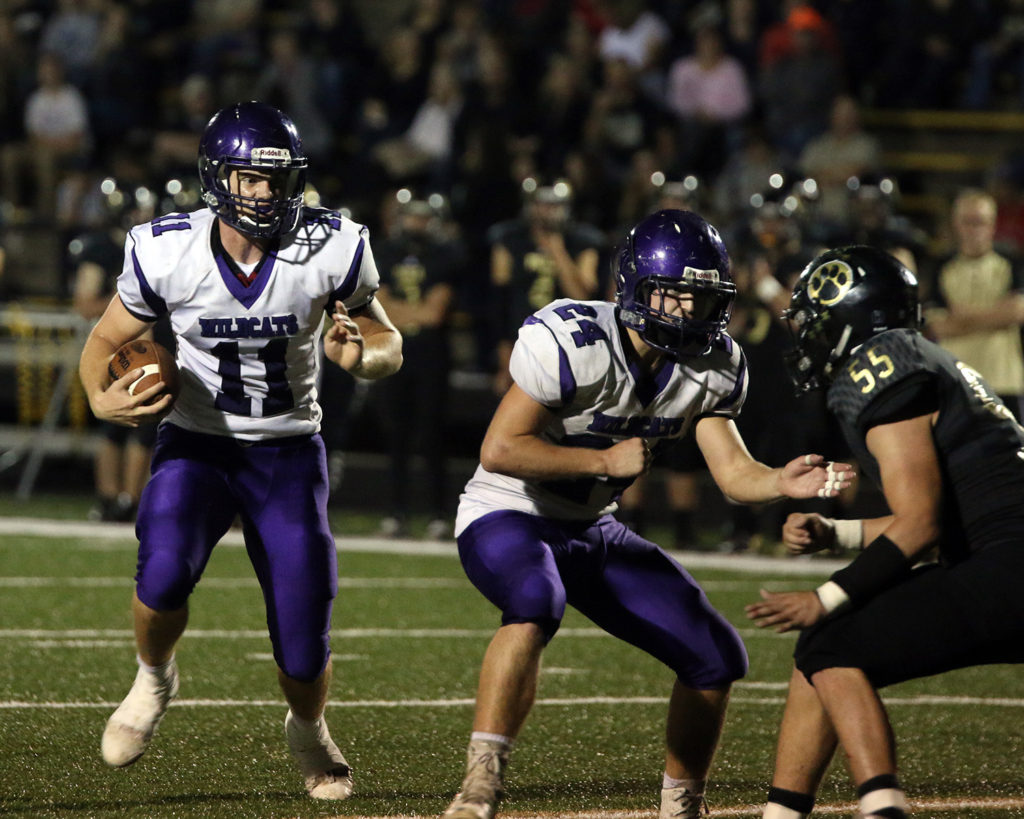 Quarterback Grant Harding waits for a block from teammate Jake Hill to get a few extra yards Friday in Paola.