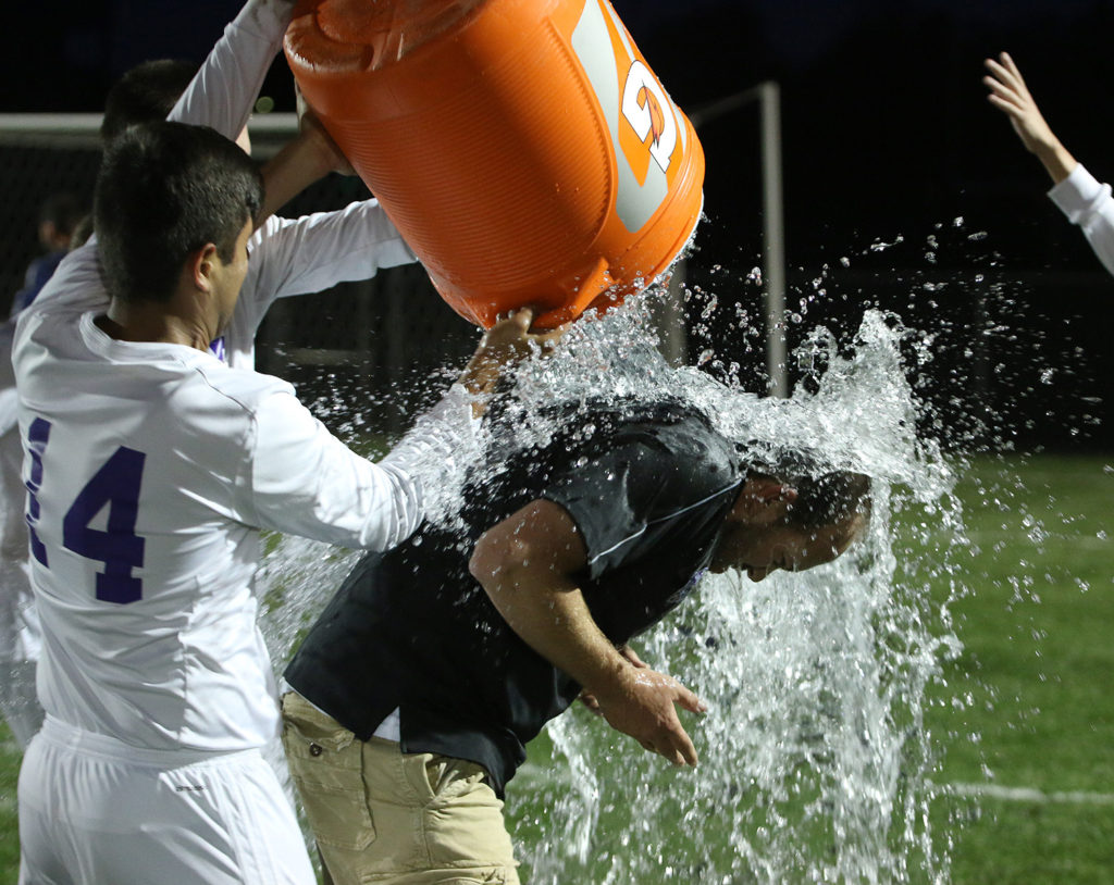 Louisburg head coach Kyle Conley is doused with cold water thanks to Herman Knipp and Eric Vazquez (14) following Tuesday's win.